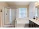 Bright bathroom featuring a glass-enclosed shower and a tub with a glass block window at 804 N Jamaica Way, Gilbert, AZ 85234