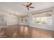 Open-concept living area with hardwood floors, a ceiling fan, large windows, and a view of the entryway at 10856 E Kiva Ave, Mesa, AZ 85209