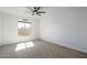 A well lit bedroom featuring carpeted floors, ceiling fan, and large window at 11529 N 170Th Ln, Surprise, AZ 85388