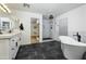 Bright bathroom with black tile floor, soaking tub, white vanity, and step-in shower at 12118 W Villa Chula Ct, Sun City, AZ 85373