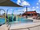 Community pool featuring a splash pad, lounge chairs, shade umbrellas, and a red building in the background at 129 N 175Th Ave, Goodyear, AZ 85338