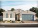 Charming single-story home with blue garage door and shutters and well manicured desert landscaping at 129 N 175Th Ave, Goodyear, AZ 85338