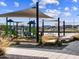 Community playground with play structures, shaded seating, and picnic tables on a sunny day with blue skies at 129 N 175Th Ave, Goodyear, AZ 85338