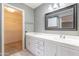 Bathroom with white vanity, black framed mirror, tile floors and view to walk-in closet at 14510 W Yosemite Dr, Sun City West, AZ 85375