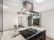 Kitchen island cooktop with stainless steel range hood, and a view to the outside patio at 1517 E Dunbar Dr, Tempe, AZ 85282