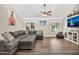 View of living room with hardwood floors, a gray sectional and bright light entering from the large window at 1565 W Plana Ave, Mesa, AZ 85202