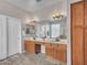 Bathroom with dual sinks, wood cabinets, and a large mirror with decorative lighting at 15819 W Ripple Rd, Goodyear, AZ 85338