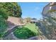 Green backyard with stone borders, patio seating, mature trees, and a blue sun umbrella at 17210 N Firestone Ln, Surprise, AZ 85374