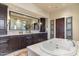 Luxurious bathroom featuring a double vanity, granite countertops, and a soaking tub at 18683 N 101St Pl, Scottsdale, AZ 85255