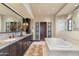 Luxurious bathroom featuring a double vanity, granite countertops, and a soaking tub at 18683 N 101St Pl, Scottsdale, AZ 85255