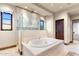 Well-lit bathroom with a tub and shower enclosed with clear glass near a bedroom at 18683 N 101St Pl, Scottsdale, AZ 85255