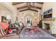 Elegant living room with a stone fireplace, wood beam ceilings, and comfortable leather seating at 18683 N 101St Pl, Scottsdale, AZ 85255