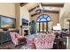 Spacious living room featuring wood beam ceilings, a stone fireplace, and a large arched window at 18683 N 101St Pl, Scottsdale, AZ 85255