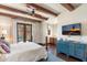 Bright main bedroom with beamed ceiling, blue accent cabinet, and a door leading to a private patio at 18683 N 101St Pl, Scottsdale, AZ 85255