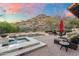 Beautiful pool and spa area with a rock waterfall feature, surrounded by desert landscape and mountain views at 18683 N 101St Pl, Scottsdale, AZ 85255