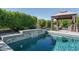 A serene backyard pool featuring a waterfall feature, lush landscaping, and a covered lounge area for relaxation at 18811 W San Miguel Ave, Litchfield Park, AZ 85340