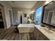 Bathroom featuring dual vanities, a soaking tub, and wood-look tile flooring at 1925 E La Costa Dr, Gilbert, AZ 85298