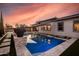 Beautiful backyard pool with stone accents, an awning, and modern pavers surrounded by synthetic grass at 1925 E La Costa Dr, Gilbert, AZ 85298