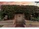 Private gate with a detailed face surrounded by lush green foliage and planters at 2169 E Alameda Dr, Tempe, AZ 85282