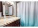 Bathroom featuring granite countertop, wood cabinet, stainless steel faucet, and tiled shower with patterned curtain at 2744 E Windrose Dr, Phoenix, AZ 85032