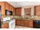 Close-up of kitchen featuring wooden cabinets, granite countertops, tile floors and black appliances at 3127 W Apollo Rd, Phoenix, AZ 85041