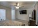 Bright bedroom featuring a ceiling fan, mounted TV, light gray wood floors, and bathroom access at 3210 W Belmont Ave, Phoenix, AZ 85051