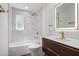 Bright bathroom featuring marble style tiles in shower and bath, sleek vanity and a modern backlit mirror at 3707 E Amelia Ave, Phoenix, AZ 85018