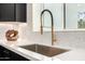 Close up of a kitchen sink, quartz countertop, modern faucet and a tile backsplash at 3707 E Amelia Ave, Phoenix, AZ 85018