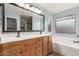 Bathroom featuring double sink vanity, soaking tub, large framed mirror, and natural light at 3891 E Melrose St, Gilbert, AZ 85297