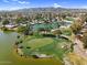 Aerial image of a scenic golf course with a lake, surrounded by homes and distant mountains under a partly cloudy sky at 4826 E Navajo Cir, Phoenix, AZ 85044