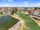 Aerial view of a lush golf course with a pond and residential area under a clear sky. Golf cart path visible at 4826 E Navajo Cir, Phoenix, AZ 85044