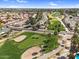 Aerial view of a residential area around a golf course with lush green fairways and tree-lined streets under a bright sky at 4826 E Navajo Cir, Phoenix, AZ 85044