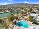 An aerial view showcases a pool with lounge chairs, a lake, and nearby homes with mountain views at 4826 E Navajo Cir, Phoenix, AZ 85044