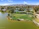 Overhead perspective shows a golf course with a central lake, bordered by houses, trees, and distant mountains under a clear sky at 4826 E Navajo Cir, Phoenix, AZ 85044