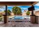 Covered outdoor patio area overlooking a refreshing pool with rock detail and a large tree at 7910 W Spur Dr, Peoria, AZ 85383