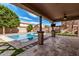 Inviting covered patio with stone flooring, a ceiling fan, and a view of the sparkling swimming pool at 7910 W Spur Dr, Peoria, AZ 85383