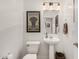 Stylish powder room featuring a pedestal sink, decorative mirror, and modern lighting fixtures at 7910 W Spur Dr, Peoria, AZ 85383