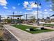 Community park area with playground, cornhole, seating, shade structures, and manicured landscaping, under a blue sky with clouds at 81 S 176Th Dr, Goodyear, AZ 85338