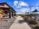 Outdoor community pool area featuring covered patios, umbrellas, landscaping, and walkway under a blue sky with clouds at 81 S 176Th Dr, Goodyear, AZ 85338