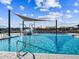 A community pool with a splash pad, surrounded by lounge chairs, under shade structures, and blue skies with light clouds at 81 S 176Th Dr, Goodyear, AZ 85338