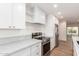 Kitchen with white cabinets, marble countertops, stainless steel appliances, and open shelving at 829 E Desert Park Ln, Phoenix, AZ 85020