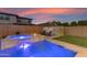 Backyard featuring a pool, hot tub, mural, and green space at dusk at 9730 E Resistance Ave, Mesa, AZ 85212