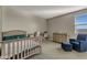 Neutral bedroom featuring a crib, dresser, soft carpet, and comfortable seating at 9759 E Satellite Dr, Mesa, AZ 85212