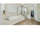 Bright bathroom featuring a soaking tub, glass-enclosed shower, and plantation shutters for privacy at 10049 E Topaz Ave, Mesa, AZ 85212