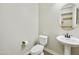 Powder room with a toilet, sink, round mirror, and plenty of open space for storage at 10049 E Topaz Ave, Mesa, AZ 85212