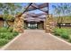 Elegant clubhouse entrance with stone pillars, a covered walkway, and lush landscaping creates a grand arrival experience at 10049 E Topaz Ave, Mesa, AZ 85212
