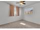 Bright bedroom featuring neutral carpet, a window with pinkish curtains, and a ceiling fan at 1007 W 5Th St, Mesa, AZ 85201