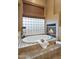 Soaking tub and fireplace with views through glass block window providing natural light and privacy at 10886 E Ludlow Dr, Scottsdale, AZ 85255