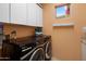 Laundry room features modern washer and dryer, storage cabinets and a bright window at 10886 E Ludlow Dr, Scottsdale, AZ 85255