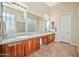 Bathroom with a large mirror, dual sinks, wood cabinets, and a glass block wall at 1320 W Whitman Dr, Anthem, AZ 85086
